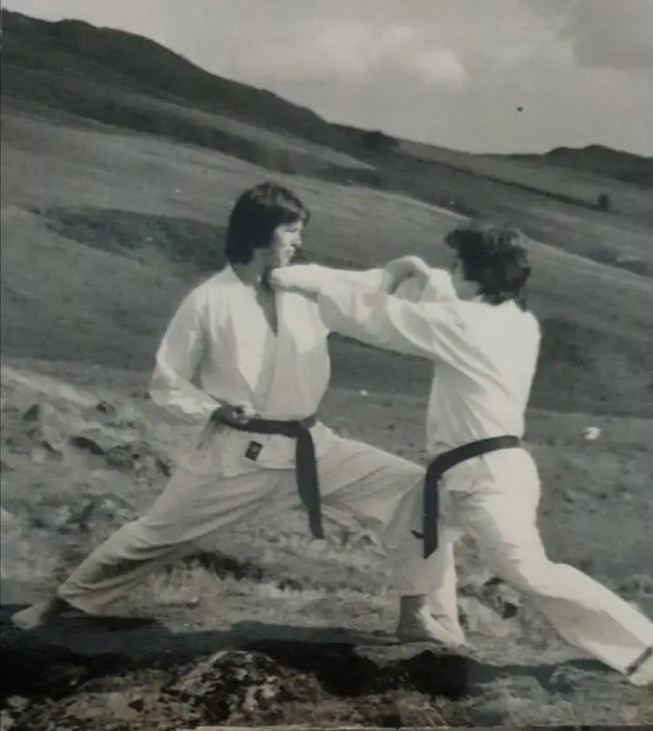 Black and white archive photo of two members sparring on a hillside