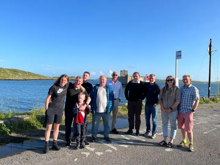 Members on the shore on Barra with the castle behind