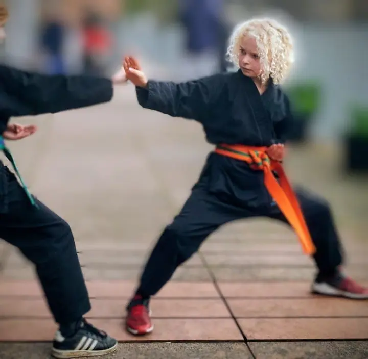 A junior in a black gi in a fighting stance