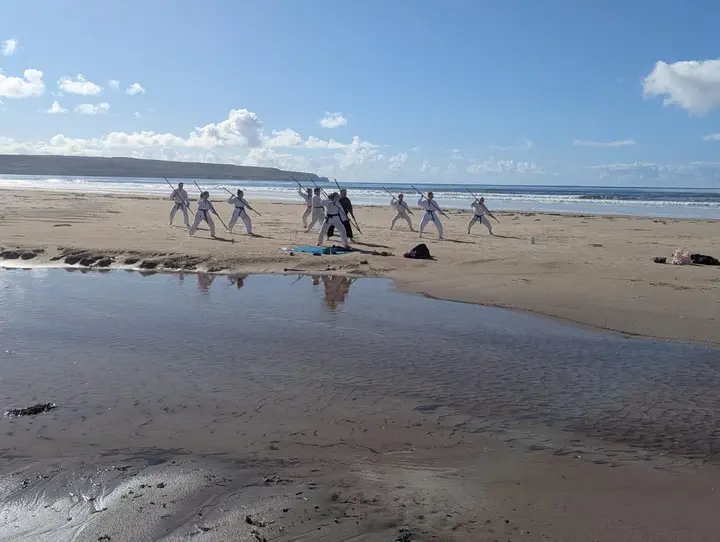 Members training on wet sand reflecting the sky